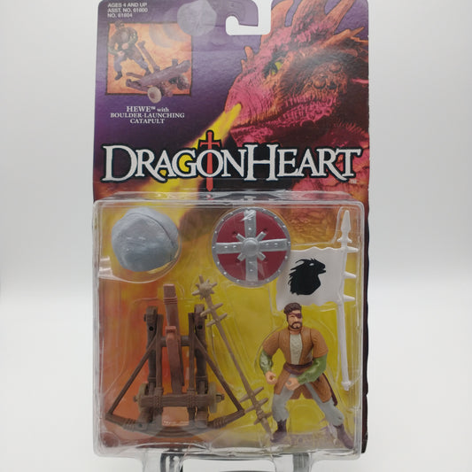 The front of the cart and bubble. The cart has an image of a red dragon breathing fire from its nostrils and text that reads "Dragonheart". The bubble contains the Hewe action figure along with several accessories including a boulder, a catapult, a shield, and a flag. 