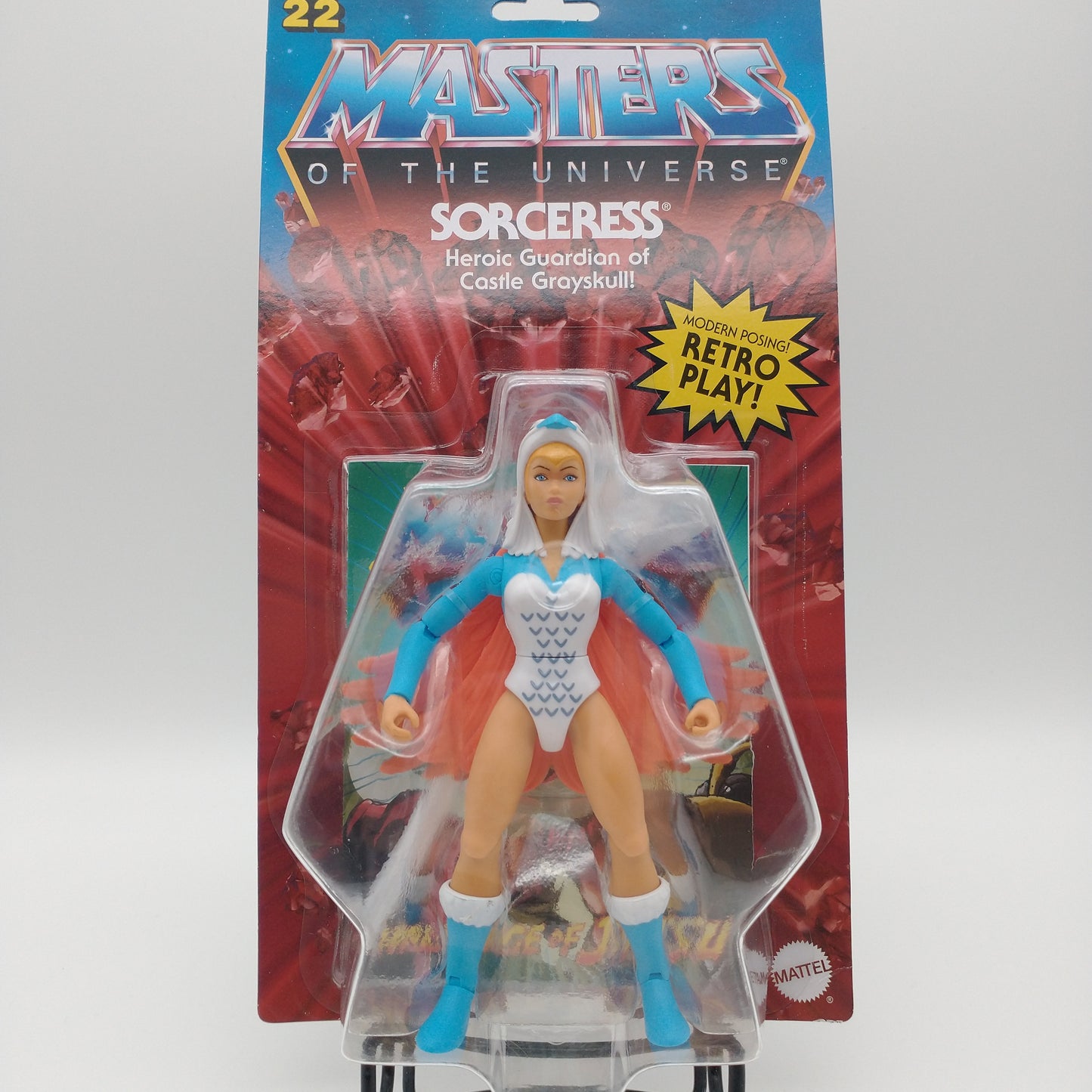 The front of the box and bubble. The bubble is sealed, the action figure inside is standing with her arms out, wearing a white leotard with blud feather decals, and a hood with a blue beak.