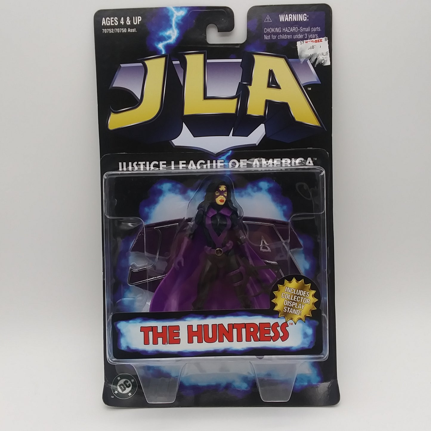 The front of the box and bubble. The bubble is sealed, the action figure inside is a white woman wearing a black jumpsuit with a purple cape and purple highlights.