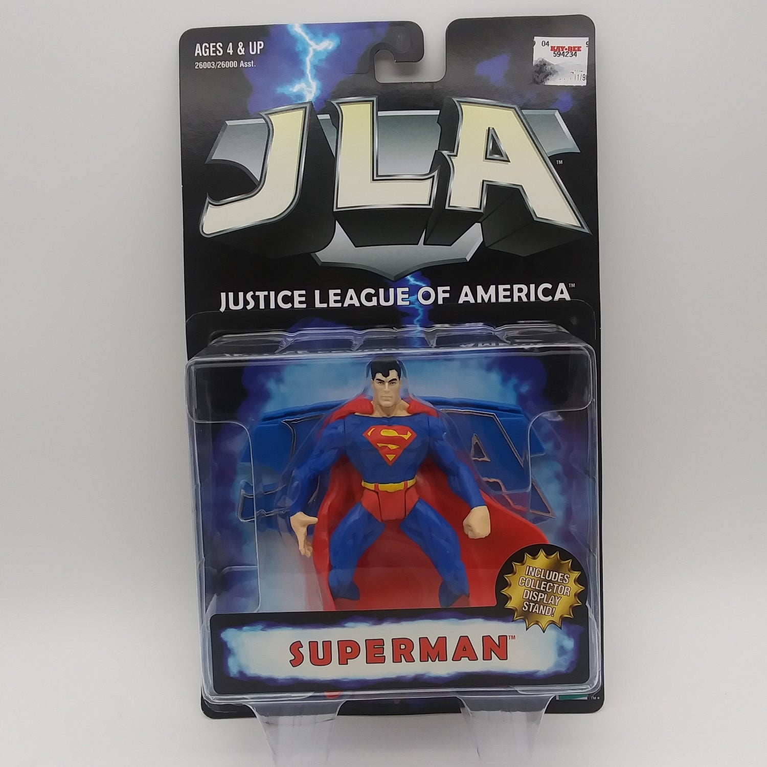 The front of the box and bubble. The bubble is sealed, the action figure inside is a white man with black hair, a red cape, a red leotard, and blue pants, a blue shirt.