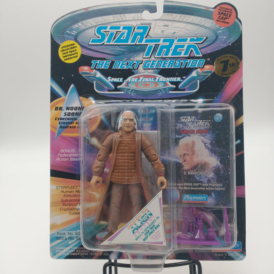 The front of the box and bubble. The bubble is sealed, the action figure inside is an elderly man with white hair, a long brown coat, and a brown tunic shirt.