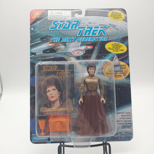 The front of the box and bubble. The bubble is sealed, the action figure inside has brown hair, a yellow greenish shirt, and a long dark red skirt.