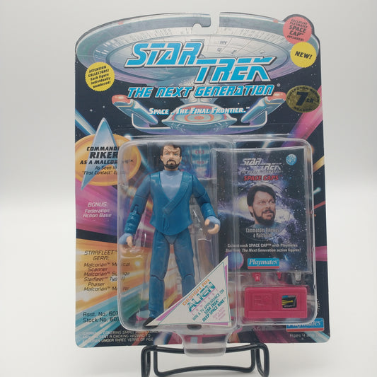 The front of the box and bubble. The bubble is sealed, the action figure inside is wearing a dark teal suit with a light blue undershirt