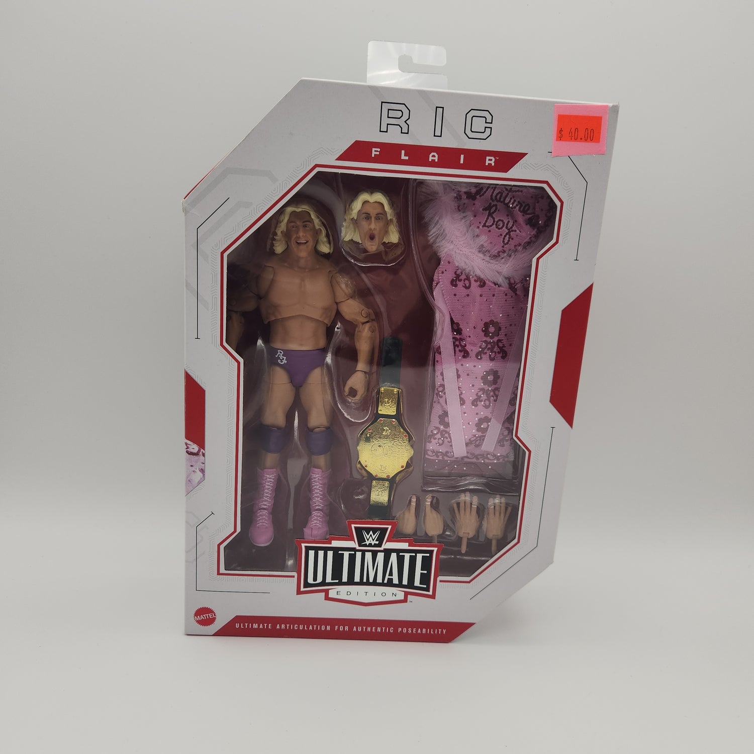 The front of the box. The bubble is intact and sealed. The action figure inside is a tan man wearing a purple speedo, pink boots, and has yellow hair. 