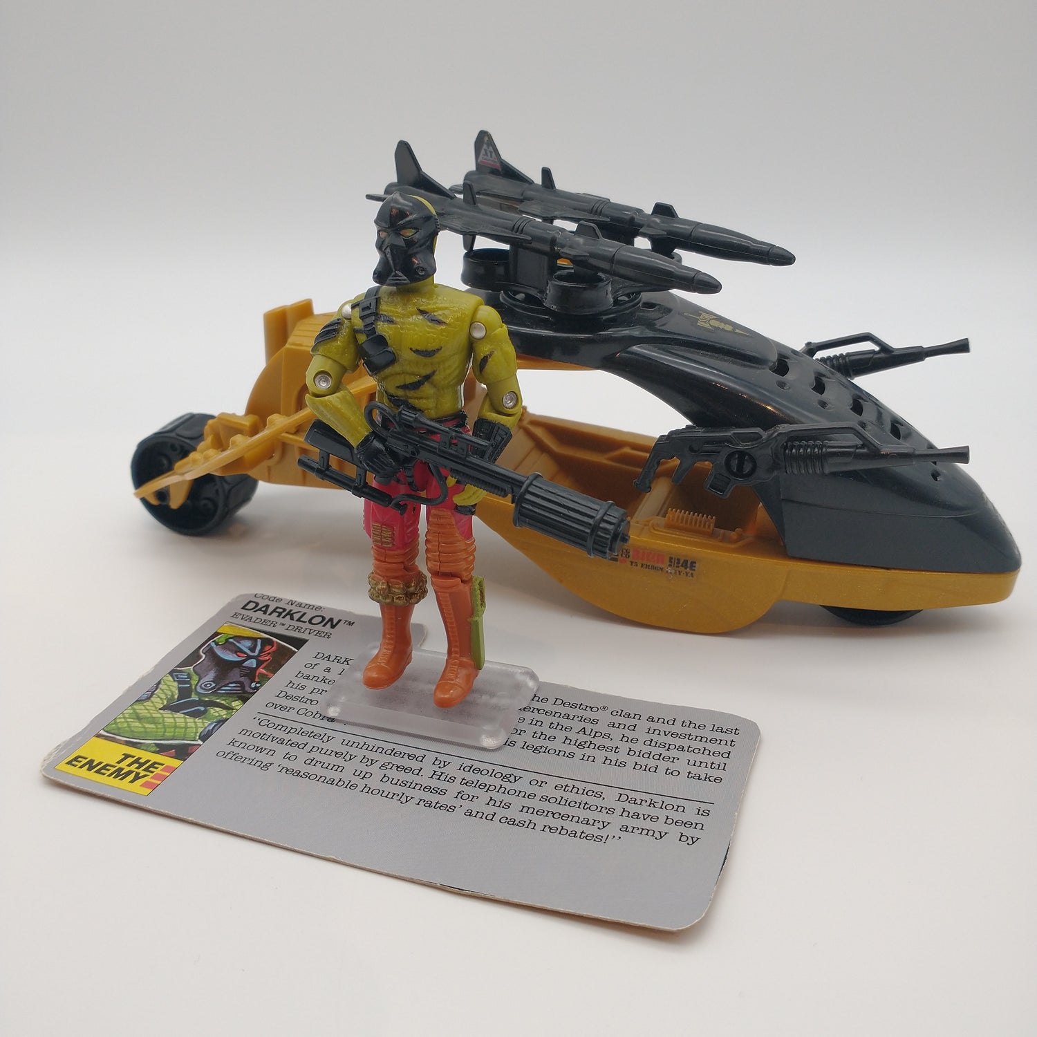 The action figure standing in front of the card with accessories