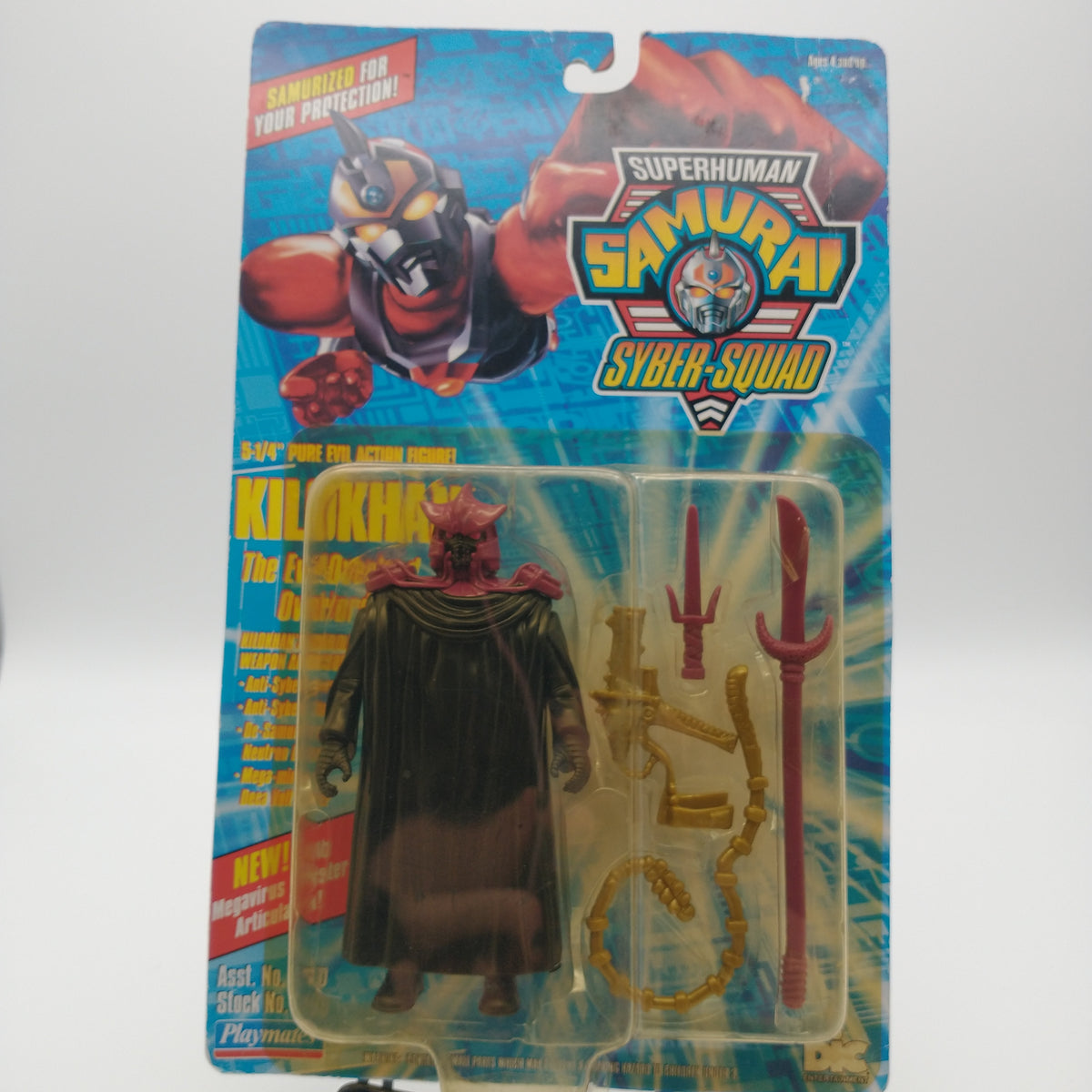 A picture of the front card and bubble. The bubble is slightly yellowed. It contains the action figure of Klokhan wearing a red cowl and black cloack, his weapons are next to him in the bubble. They include a red dagger, a red spear, a gold whip, and a gold gun.